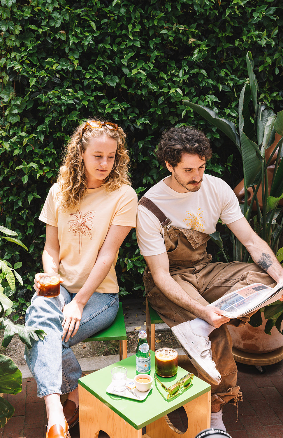 Man with a cream t shirt with a banana and sunglasses in buen dia coffee and a woman wearing a yellow t shirt and drinking a coffee