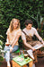 Man with a cream t shirt with a banana and sunglasses in buen dia coffee and a woman wearing a yellow t shirt and drinking a coffee