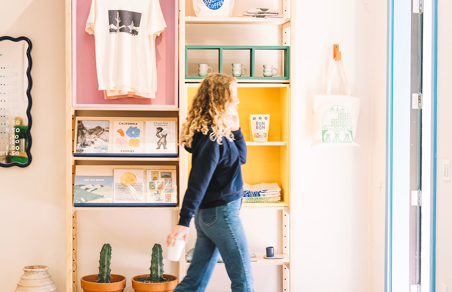 Girl in Buen Dia coffee shop, walking with a cup of coffee and a navy blue sweatshirt