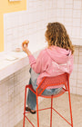 Woman eating pastries in a coffee shop with a pink sweater 