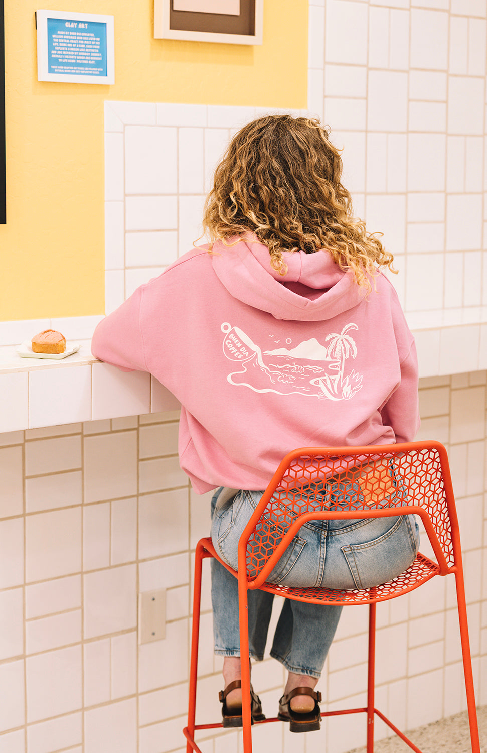Woman sitting in a coffee shop with a pink hoodie in san luis obispo